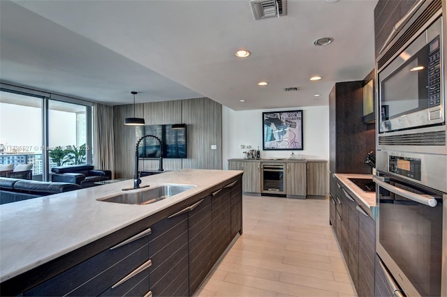 kitchen featuring appliances with stainless steel finishes, pendant lighting, sink, beverage cooler, and floor to ceiling windows