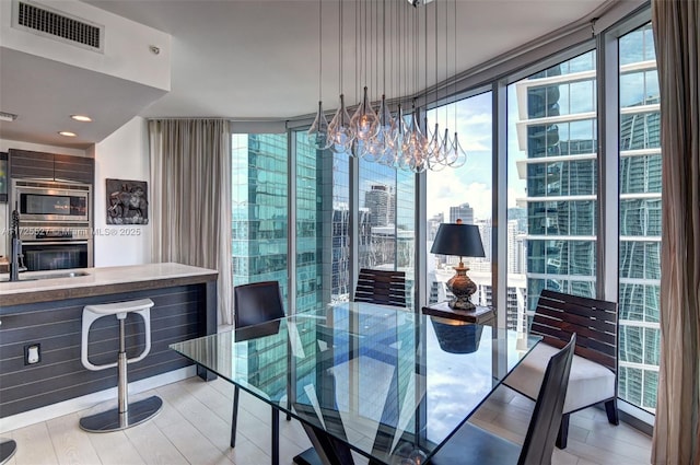 dining space with expansive windows and light wood-type flooring