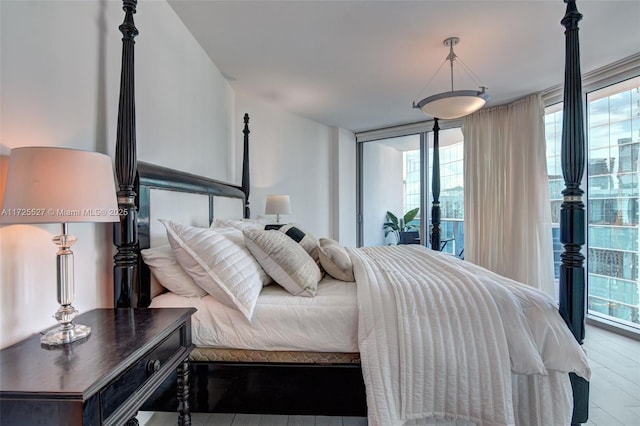 bedroom with hardwood / wood-style flooring, floor to ceiling windows, and access to exterior