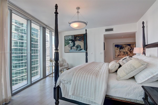 bedroom featuring wood-type flooring, access to exterior, and floor to ceiling windows