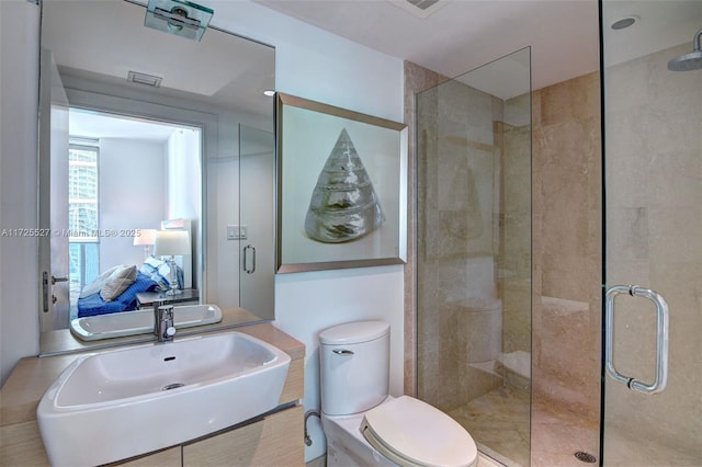 bathroom featuring a shower with door, vanity, and toilet