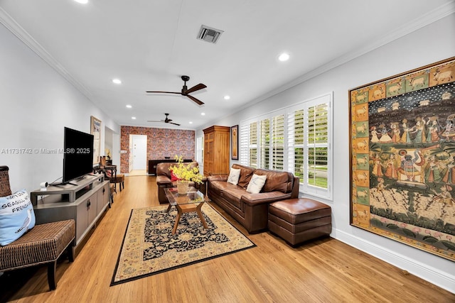 living room featuring crown molding, brick wall, and light wood-type flooring