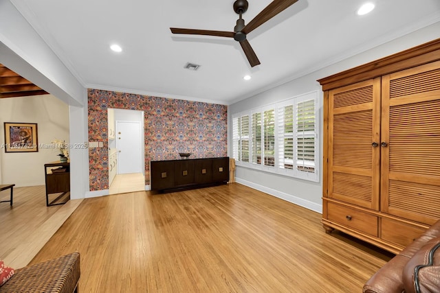 unfurnished living room with crown molding, ceiling fan, and light wood-type flooring