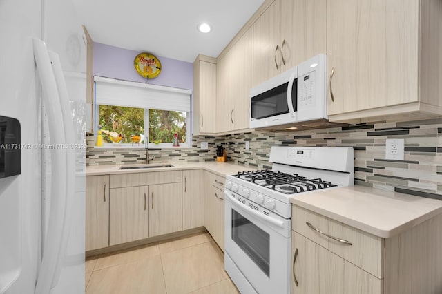 kitchen with sink, white appliances, light tile patterned floors, light brown cabinetry, and decorative backsplash