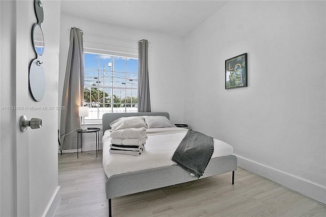 bedroom with light hardwood / wood-style floors and multiple windows