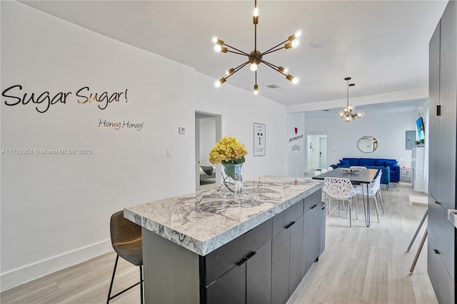 kitchen featuring gray cabinets, a center island, a chandelier, and decorative light fixtures