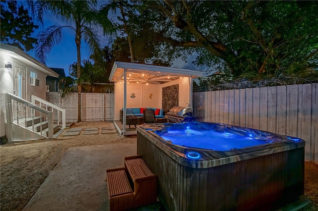 patio at twilight featuring a hot tub and an outdoor hangout area