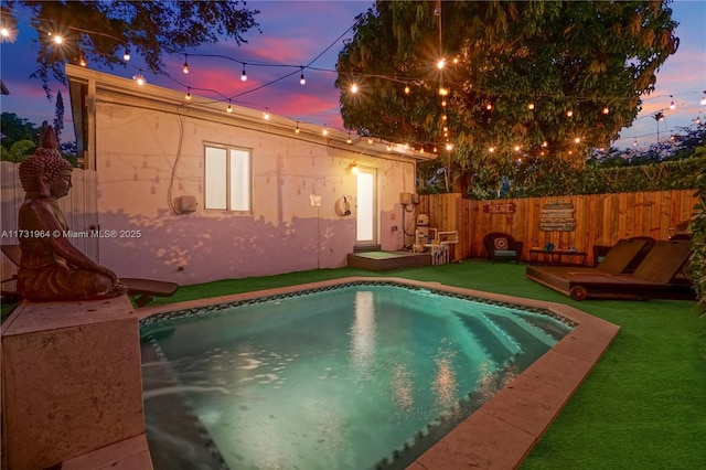 pool at dusk featuring a lawn