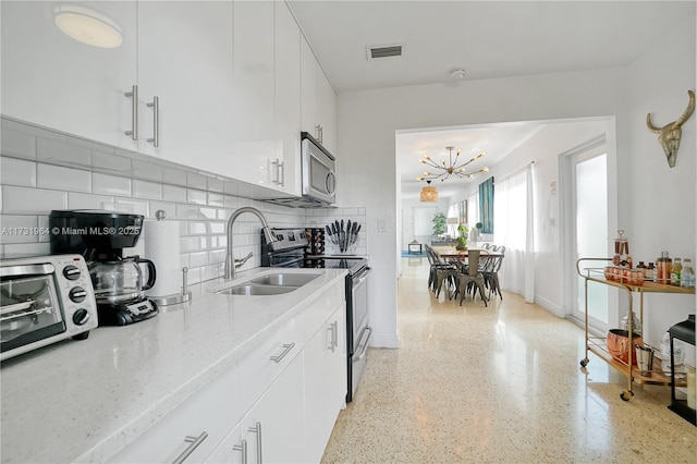 kitchen with sink, light stone counters, white cabinets, stainless steel appliances, and backsplash