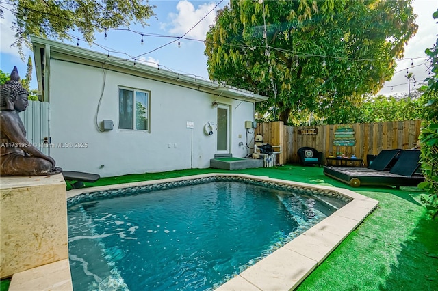 back of property with a fenced in pool