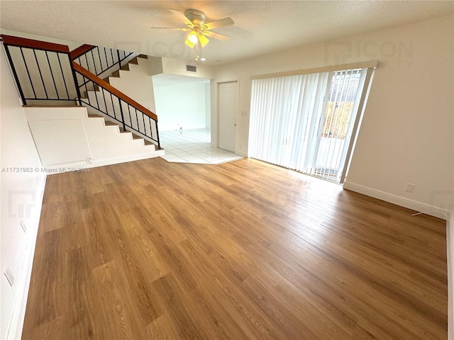 unfurnished living room featuring ceiling fan, a textured ceiling, and light hardwood / wood-style floors