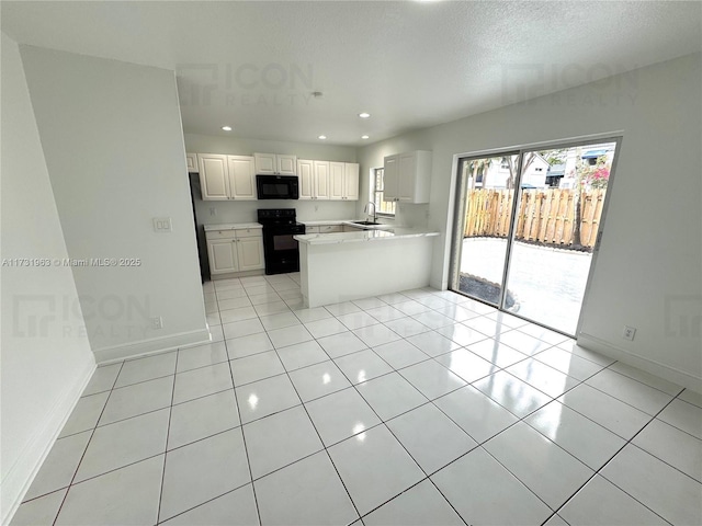 kitchen with black appliances, sink, white cabinets, light tile patterned floors, and kitchen peninsula