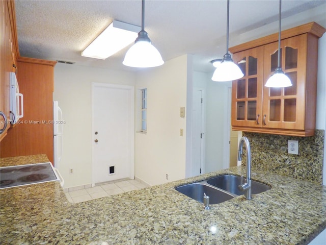 kitchen featuring decorative light fixtures, sink, decorative backsplash, kitchen peninsula, and a textured ceiling