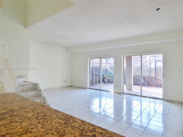 empty room with light tile patterned flooring and a textured ceiling