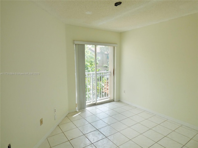 tiled empty room featuring a textured ceiling