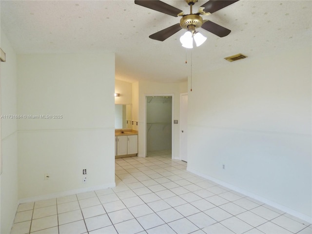 unfurnished room with light tile patterned floors, a textured ceiling, and ceiling fan