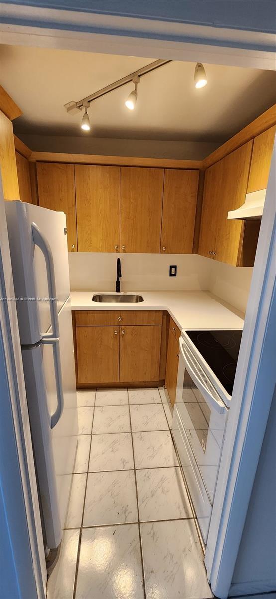 kitchen featuring electric stove, refrigerator, and sink