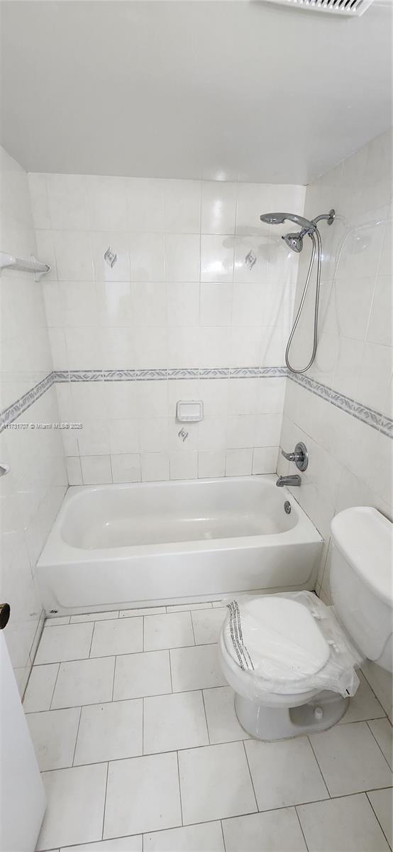 bathroom featuring tiled shower / bath, tile patterned floors, and toilet