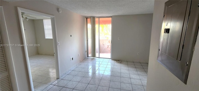 unfurnished room featuring ceiling fan, electric panel, a textured ceiling, and a wall of windows