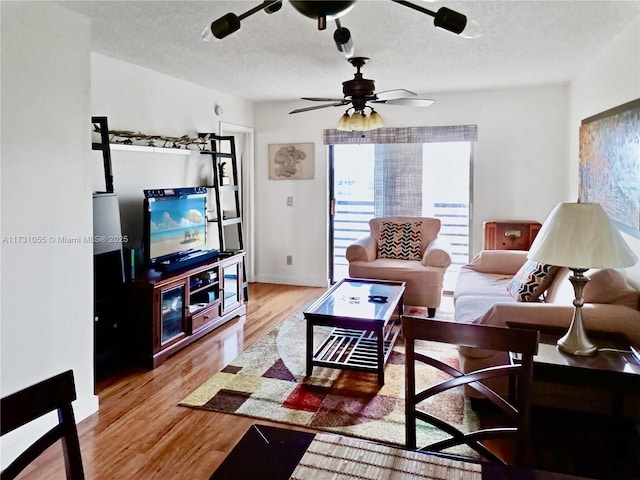 living room with hardwood / wood-style flooring, a textured ceiling, and ceiling fan