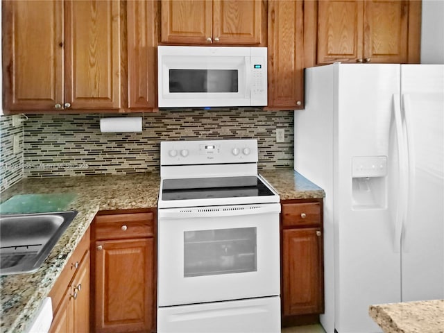 kitchen with tasteful backsplash, sink, white appliances, and light stone countertops