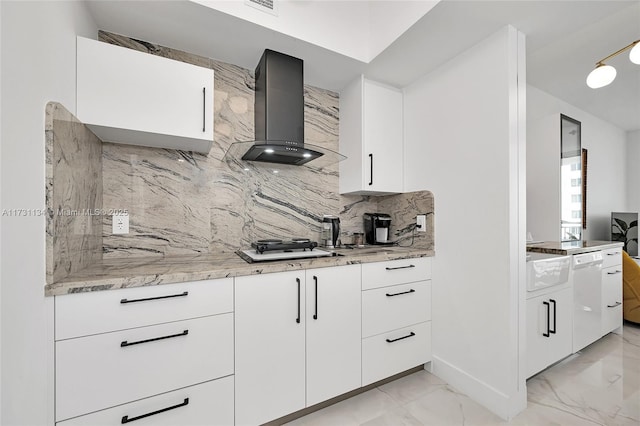 kitchen with ventilation hood, white cabinetry, light stone countertops, and backsplash