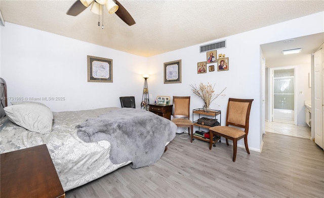 bedroom featuring ceiling fan, light hardwood / wood-style flooring, and a textured ceiling