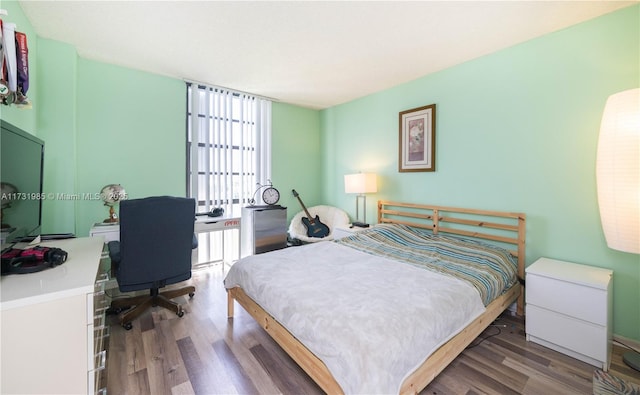 bedroom with dark hardwood / wood-style flooring and floor to ceiling windows