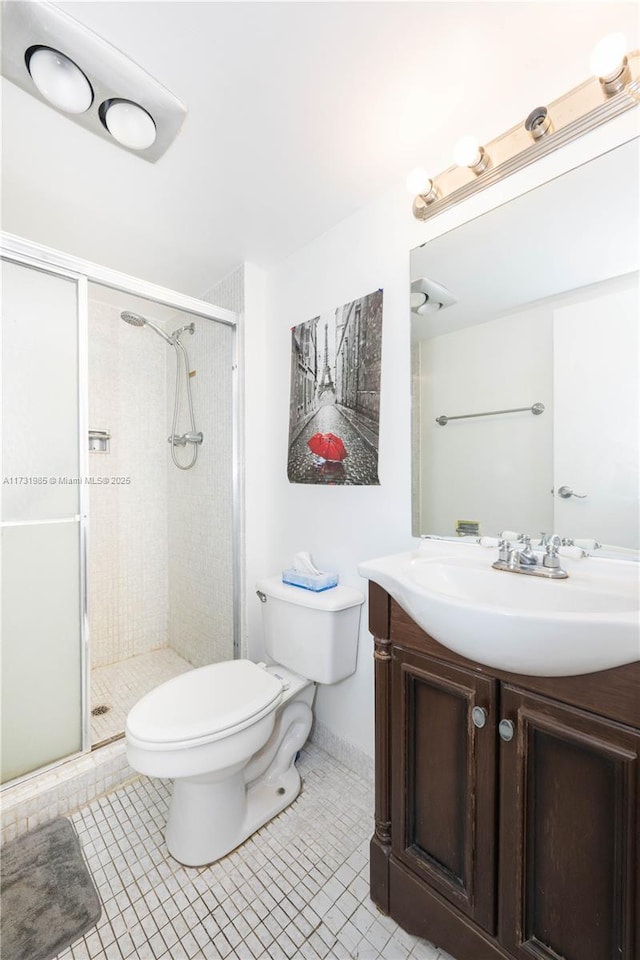 bathroom with a shower with door, vanity, tile patterned floors, and toilet