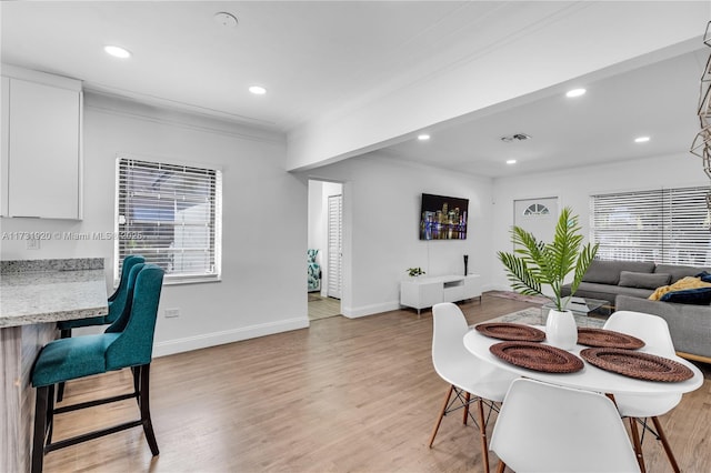 dining space featuring ornamental molding, a healthy amount of sunlight, and light wood-type flooring