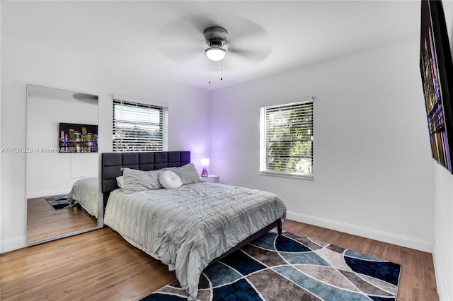 bedroom featuring hardwood / wood-style flooring, ceiling fan, and multiple windows