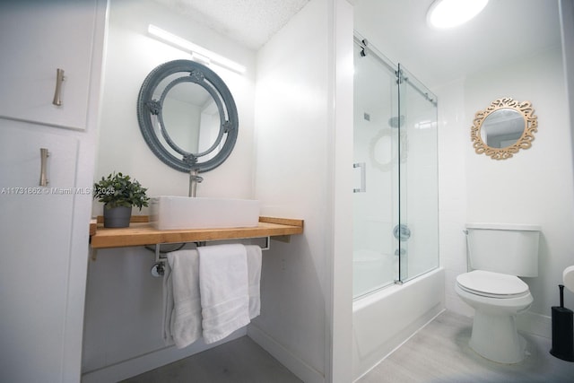 full bathroom featuring toilet, sink, a textured ceiling, hardwood / wood-style flooring, and enclosed tub / shower combo