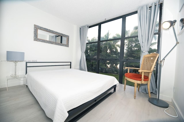 bedroom with wood-type flooring, expansive windows, and a textured ceiling