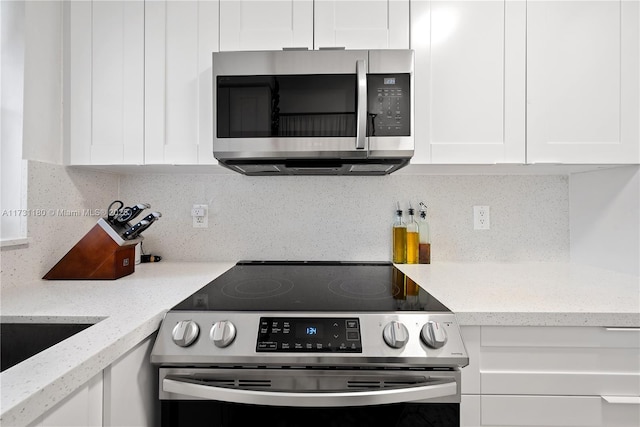 kitchen with tasteful backsplash, light stone countertops, white cabinetry, and stainless steel appliances