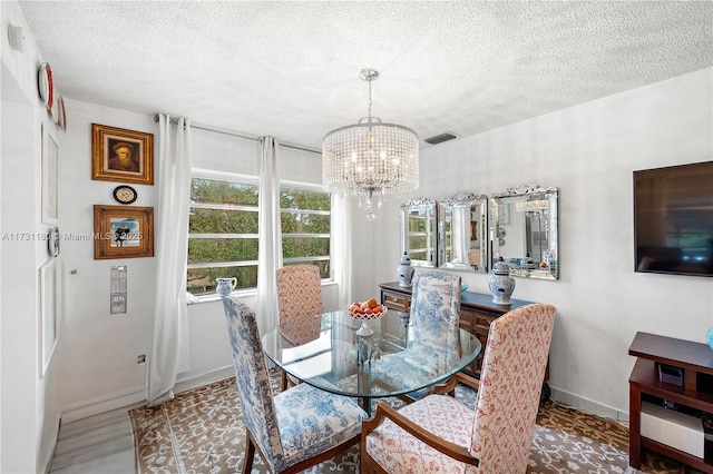 dining space with a chandelier and a textured ceiling