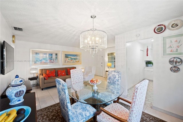 dining space with a notable chandelier, tile patterned floors, and a textured ceiling