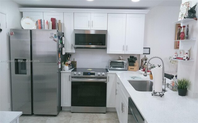 kitchen featuring white cabinetry, appliances with stainless steel finishes, sink, and light tile patterned floors