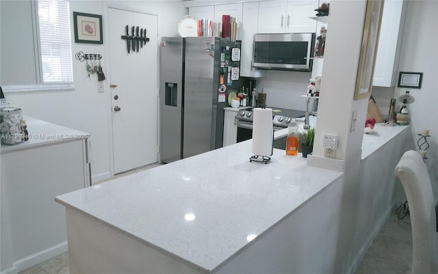 kitchen featuring white cabinetry, light stone countertops, kitchen peninsula, and appliances with stainless steel finishes