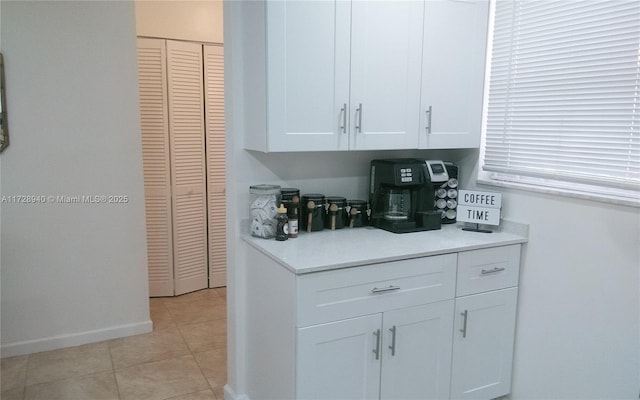 bar featuring light tile patterned floors and white cabinets