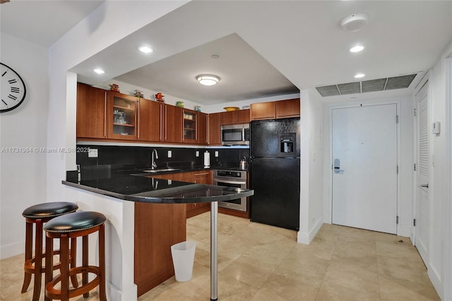 kitchen with sink, backsplash, a kitchen breakfast bar, stainless steel appliances, and kitchen peninsula