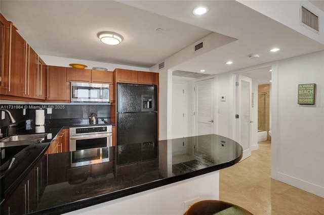 kitchen with appliances with stainless steel finishes, kitchen peninsula, sink, and backsplash