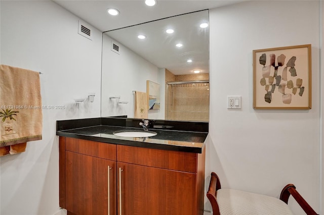 bathroom featuring a shower with door and vanity