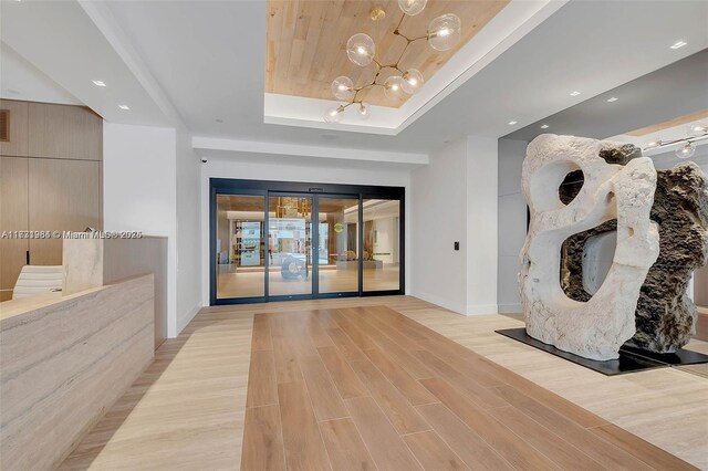 unfurnished living room with wood ceiling, a raised ceiling, and light wood-type flooring