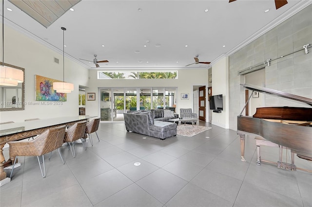 living room with ceiling fan, ornamental molding, light tile patterned floors, and a high ceiling