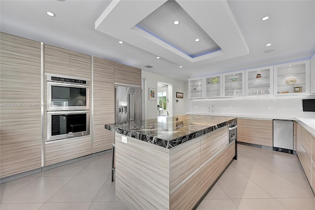 kitchen featuring a large island, light tile patterned floors, stainless steel appliances, and a raised ceiling