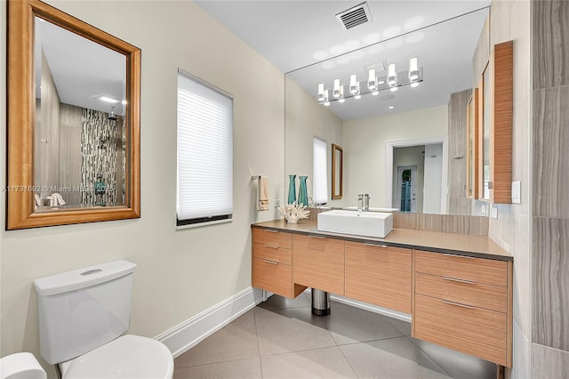 bathroom with tile patterned flooring, vanity, a wealth of natural light, and toilet