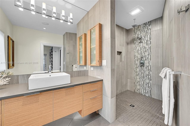 bathroom with vanity, tiled shower, tile walls, and tile patterned floors