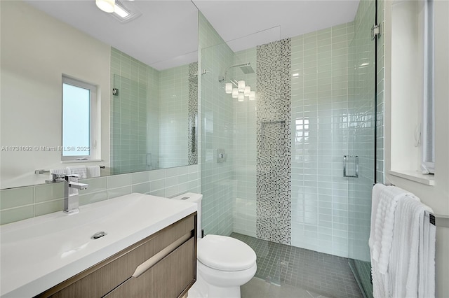 bathroom with radiator, tile walls, vanity, an enclosed shower, and toilet