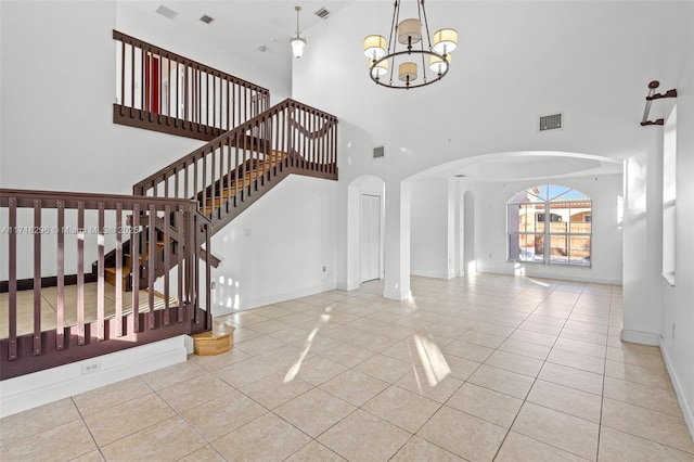 tiled entrance foyer featuring a high ceiling and an inviting chandelier