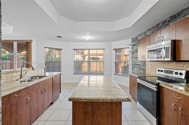 kitchen featuring light tile patterned flooring, sink, stainless steel fridge, a raised ceiling, and a kitchen island